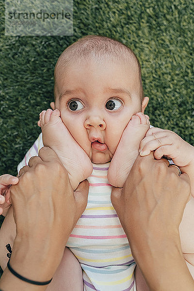 Junge Mutter und Baby beim Sport  Mädchen schaut zur Seite  Füße im Gesicht