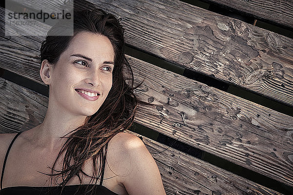 Porträt einer lächelnden jungen Frau  die sich auf dem Steg entspannt