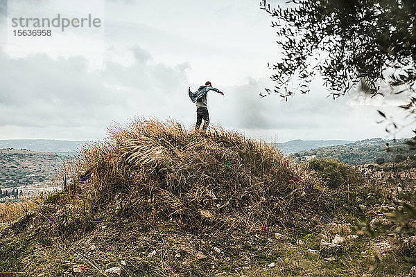 Junger Mann steht während eines Sturms auf einem Hügel  Sizilien