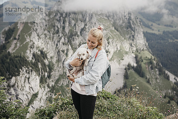 Junge lächelnde Wanderin mit Hund auf dem Aussichtspunkt