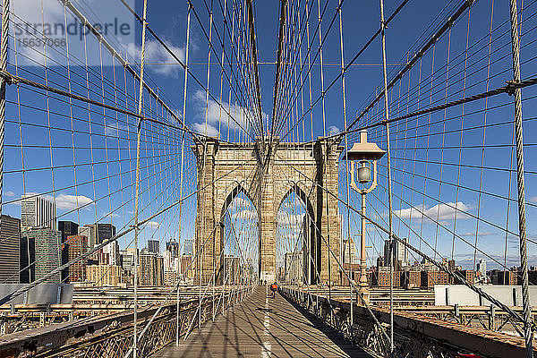 Schwindende Perspektive der Brooklyn Bridge vor blauem Himmel in New York City  USA