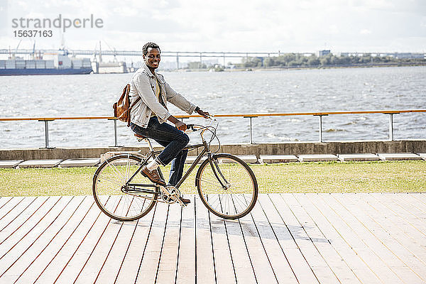 Junger Mann fährt Fahrrad am Meer