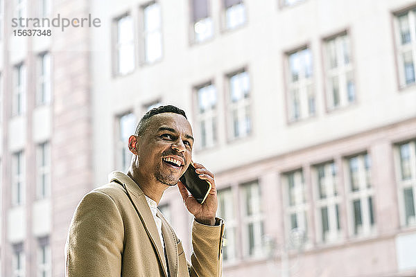 Porträt eines lachenden Geschäftsmannes am Telefon in der Stadt