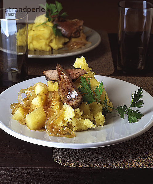 Nahaufnahme von Putenleber mit Kartoffel- und Apfelpüree in Tellern auf dem Tisch serviert