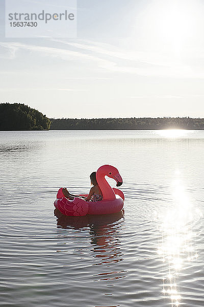 Mädchen mit Flamingo-Pool schwimmt auf einem See