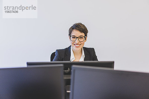 Porträt einer lächelnden jungen Geschäftsfrau am Schreibtisch im Büro