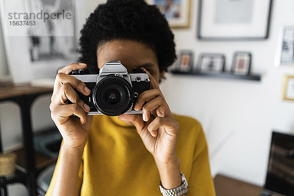 Junge Frau  die zu Hause mit einer Oldtimer-Kamera fotografiert