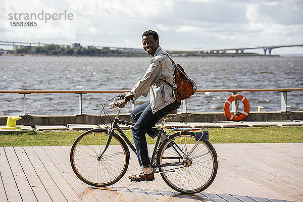 Junger Mann fährt Fahrrad am Meer