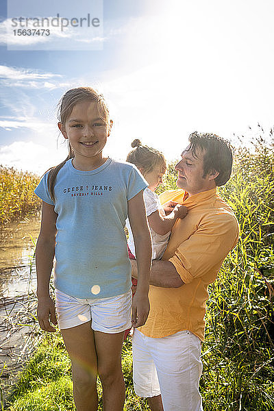 Porträt eines lächelnden Mädchens mit ihrer Familie an einem Wasserlauf  Darß  Mecklenburg-Vorpommern  Deutschland