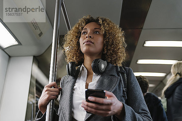 Frau mit Smartphone in der U-Bahn