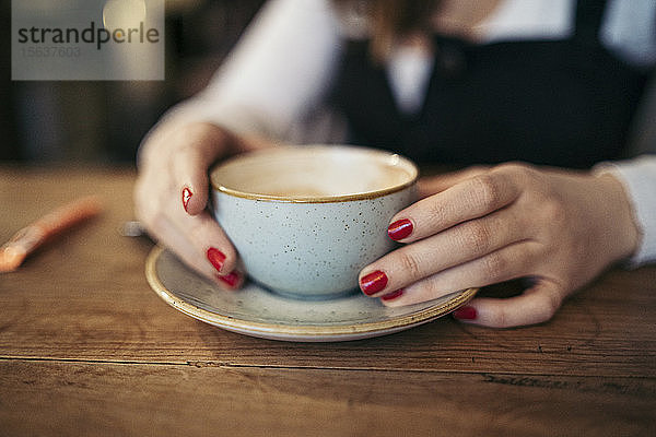 Nahaufnahme von Frauenhänden  die eine Kaffeetasse halten