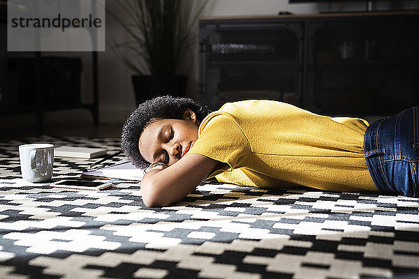 Junge Frau liegt zu Hause mit geschlossenen Augen auf dem Boden