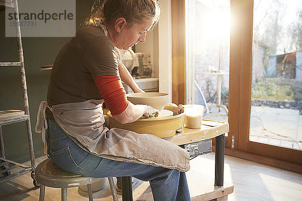 Frau  die in ihrer Werkstatt mit einer Töpferscheibe arbeitet