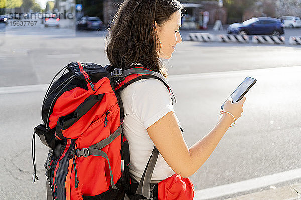 Junge Rucksacktouristin mit rotem Rucksack mit Smartphone in der Stadt  Verona  Italien