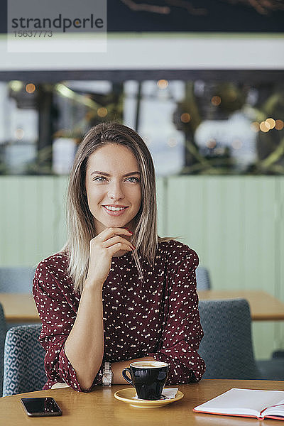 Porträt einer Frau  die in einem Cafe sitzt und Kaffee trinkt