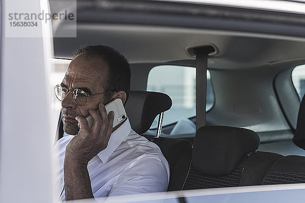 Porträt eines reifen Geschäftsmannes am Telefon im Auto