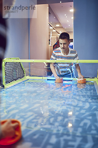Teenager spielt Airhockey in einer Spielhalle