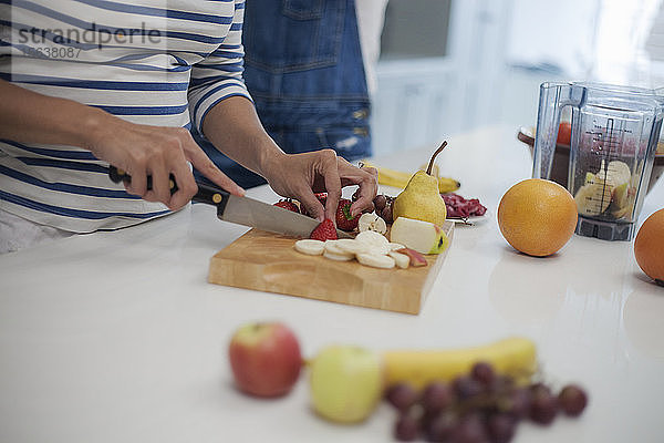 Frau hackt Früchte in der Küche  bereitet Smoothie zu