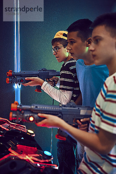 Teenager-Freunde schießen mit Gewehren in einer Spielhalle