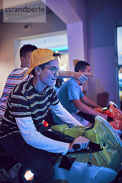 Teenager-Freunde spielen mit einem Fahrsimulator in einer Spielhalle