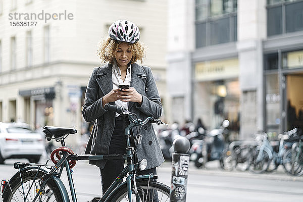 Frau mit Fahrrad und Smartphone in der Stadt  Berlin  Deutschland