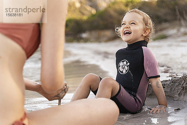 Glückliches Mädchen mit seiner Mutter am Strand