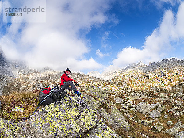 Wanderer sitzt auf einem Berg und geniesst die Aussicht  Naturpark Adamello  Italien