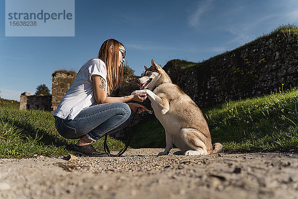 Junge Frau unterrichtet ihren Hund im Freien