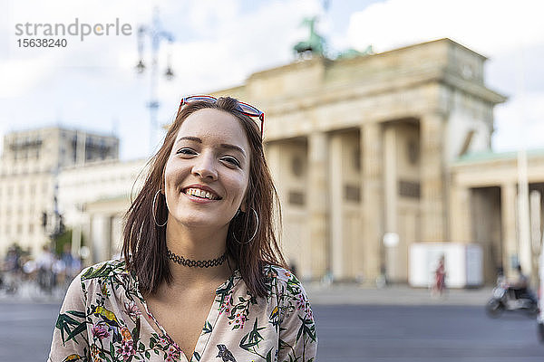 Porträt einer lächelnden jungen Frau vor dem Brandenburger Tor  Berlin  Deutschland