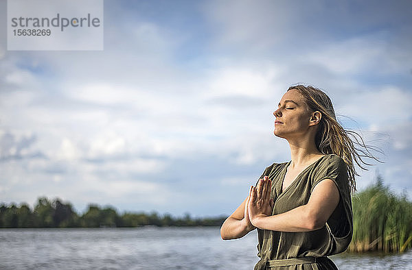 Frau meditiert an einem See