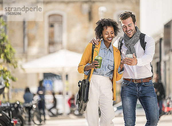 Glückliches junges Paar mit Smartphone in der Stadt