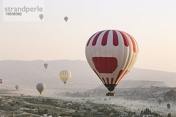 Bunte Heißluftballons fliegen über Land gegen den klaren Himmel im Goreme-Nationalpark  Türkei