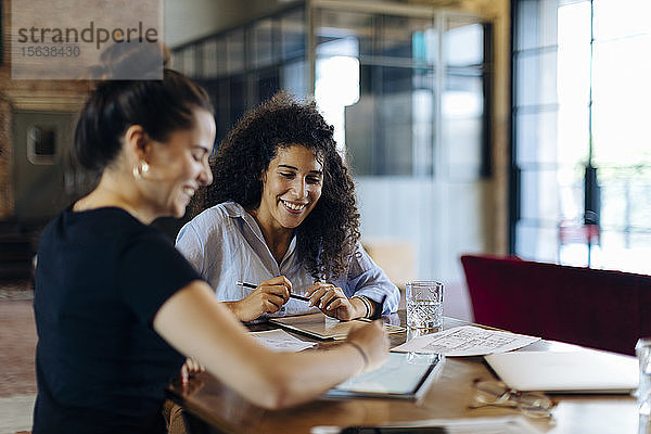 Zwei junge Geschäftsfrauen arbeiten gemeinsam am Konferenztisch im Loft-Büro