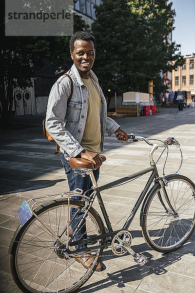 Zoung Mann pendelt in der Stadt  schiebt sein Fahrrad