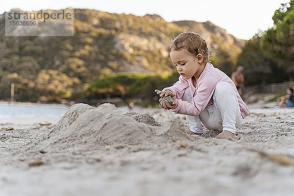Süßes Kleinkind spielt mit Sand am Strand