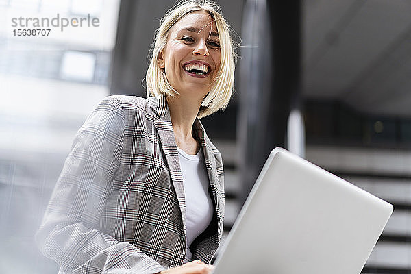 Porträt einer glücklichen jungen Geschäftsfrau mit Laptop in der Stadt