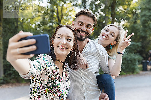 Gruppe von drei Freunden  die sich mit einem Smartphone selbstständig machen