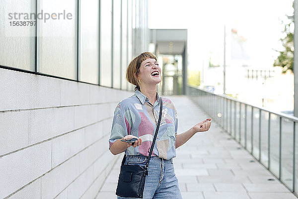 Porträt einer jungen Frau  die mit ihrem Smartphone ausflippt