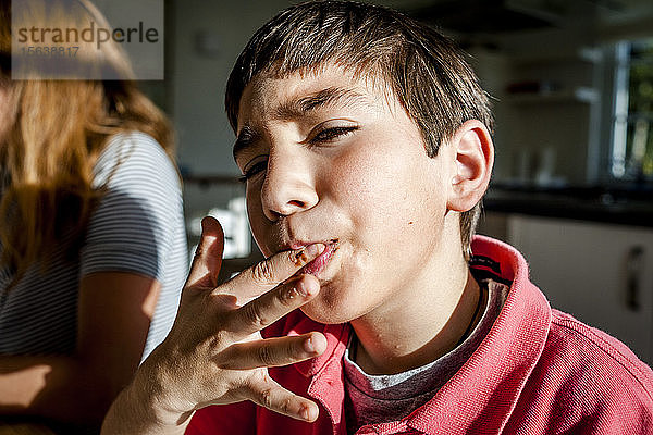 Porträt eines Jungen zu Hause  der sich den Finger leckt