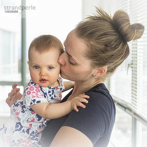 Porträt eines kleinen Mädchens mit seiner Mutter zu Hause  Mutter küsst das Baby auf die Wange; Vancouver  British Columbia  Kanada