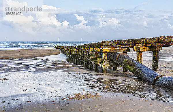 Rohrleitung zur Ableitung von Abfällen in die Nordsee am Cambois Beach mit Windkraftanlagen in der Ferne; Northumberland  England