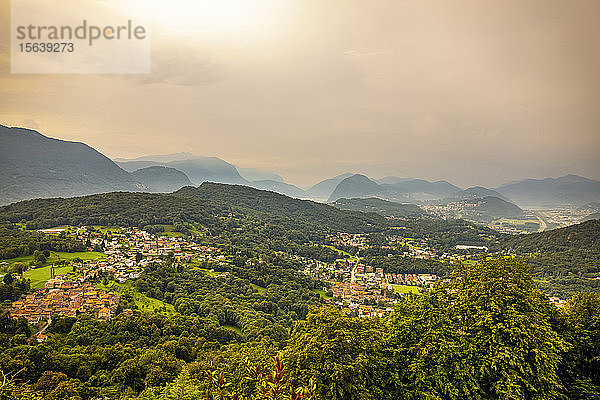 Sonnenlicht leuchtet durch den bedeckten Himmel über den sanften Hügeln von Lugano; Lugano  Tessin  Schweiz