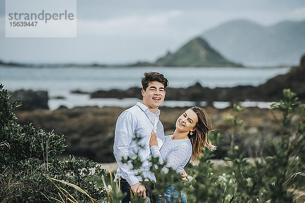 Porträt eines jungen Paares mit der zerklüfteten Küstenlinie der Nordinsel im Hintergrund; Wellington  Nordinsel  Neuseeland