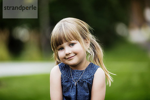 Porträt eines niedlichen jungen Mädchens mit blondem Haar in Zöpfen und einer Halskette mit einem Kreuzanhänger; Edmonton  Alberta  Kanada