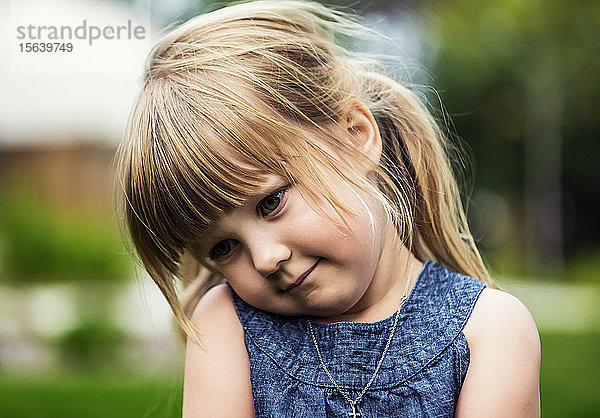 Porträt eines niedlichen jungen Mädchens mit blondem Haar  das schüchtern zu Boden schaut; Edmonton  Alberta  Kanada