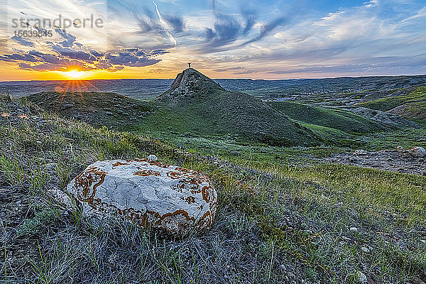 Mann steht auf einem Hügel in der weiten Landschaft  die sich bei Sonnenuntergang im Grasslands National Park bis zum Horizont erstreckt; Val Marie  Saskatchewan  Kanada