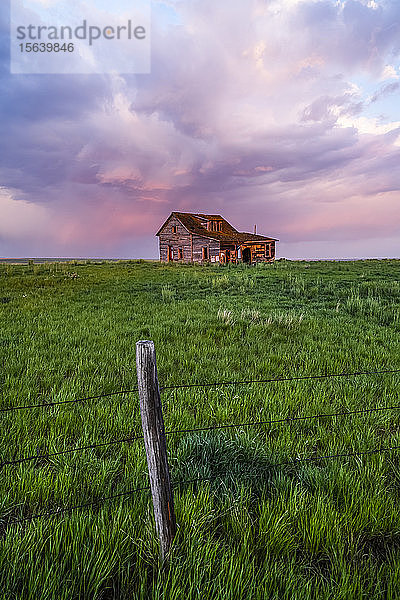 Verlassene Scheune auf Ackerland mit rosa leuchtenden Gewitterwolken; Val Marie  Saskatchewan  Kanada