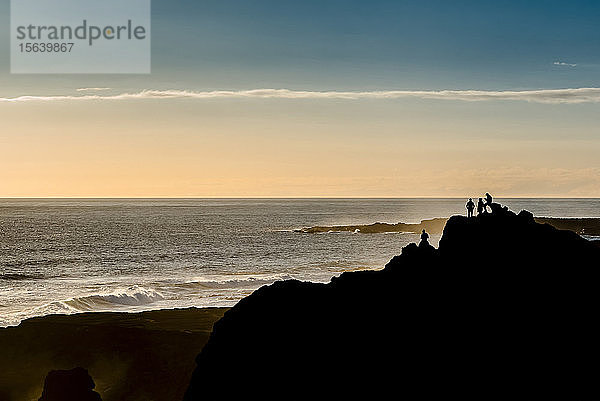 Freunde genießen die Aussicht in der Nähe des Reykjanes-Leuchtturms bei Sonnenuntergang  Halbinsel Reykjanes; Island