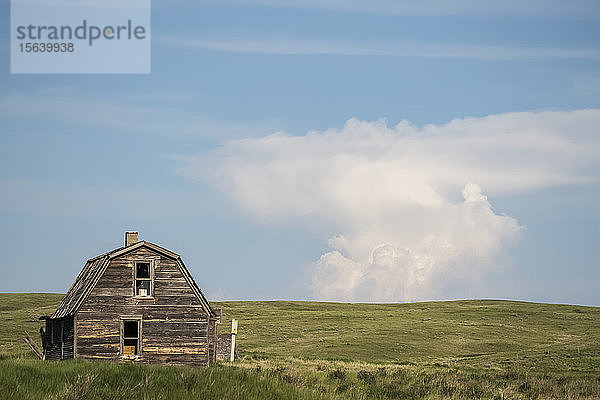Verlassene Scheune auf Ackerland mit einzigartiger Wolkenformation in der Ferne; Val Marie  Saskatchewan  Kanada