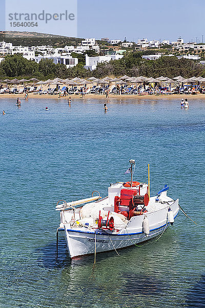 Im Wasser vertäutes Fischerboot mit Schwimmern und Sonnenanbetern in der Santa Maria Beach Area; Insel Paros  Kykladen  Griechenland